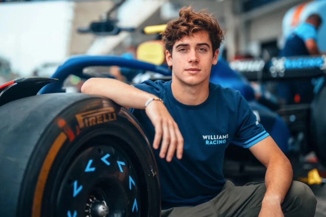 Franco Colapinto with his arm resting on the tyre of the Williams F1 car